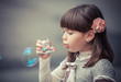 Portrait of funny lovely little girl blowing soap bubble
