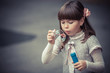 Portrait of funny lovely little girl blowing soap bubble