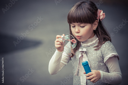 Photo: Portrait of funny lovely little girl blowing soap bubble Portrait of funny lovely little girl blowing soap bubble