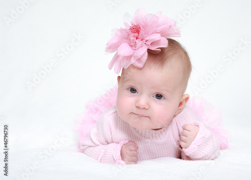 Photo: Portrait of a baby girl with a flower on her head on a white bac Portrait of a baby girl with a flower on her head on a white bac