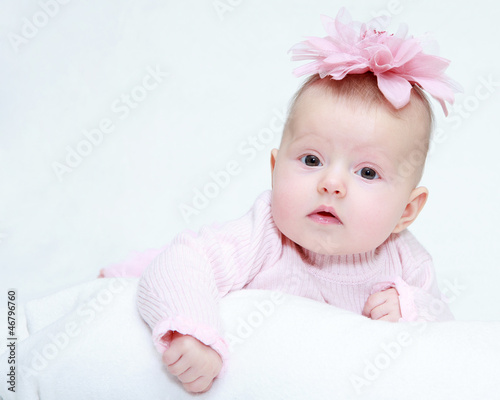 Photo: Portrait of a baby girl with a flower on her head on a white bac Portrait of a baby girl with a flower on her head on a white bac