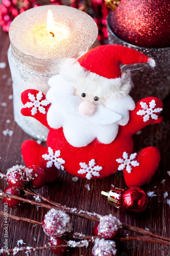Photo: Santa Claus and Christmas candle on the old wooden background Santa Claus and Christmas candle on the old wooden background
