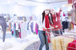 Photo: Happy friends shopping with trolley at the mall Happy friends shopping with trolley at the mall