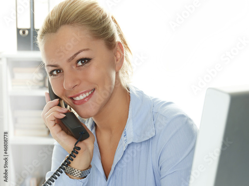 Photo: Female office assistant has a call at the office Female office assistant has a call at the office