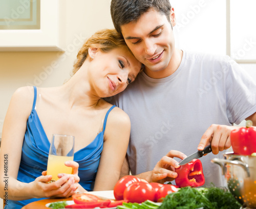 Photo: Cheerful young cooking couple at home Cheerful young cooking couple at home