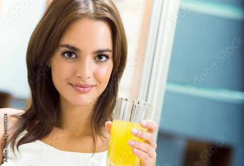Photo: Cheerful young woman with orange juice at home Cheerful young woman with orange juice at home