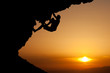 silhouette of man climbing on overhanging rock