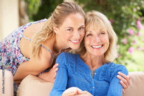 Photo: Senior Woman With Adult Daughter Relaxing On Sofa At Home Senior Woman With Adult Daughter Relaxing On Sofa At Home