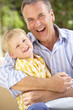 Grandfather And Grandson Relaxing On Sofa Together