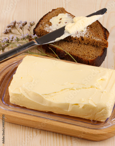 Photo: Butter on wooden holder and bread on wooden table close-up Butter on wooden holder and bread on wooden table close-up