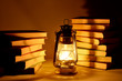 Burning kerosene lamp and books, concept magic of light