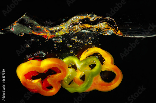 Photo: Slices of fresh red, green and yellow pepper falling into water Slices of fresh red, green and yellow pepper falling into water