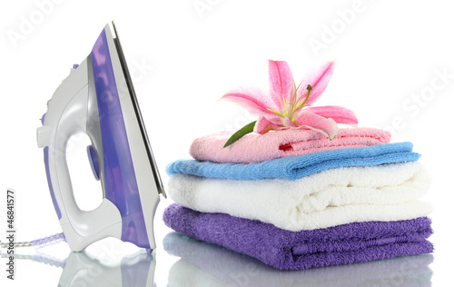 Photo: Pile of clothes with lily and electric iron, isolated on white Pile of clothes with lily and electric iron, isolated on white