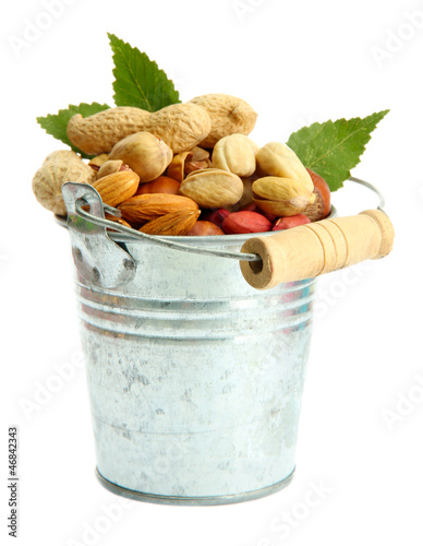 Photo: assortment of tasty nuts with leaves in pail, isolated on white assortment of tasty nuts with leaves in pail, isolated on white