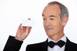 senior in a suit holding a business card