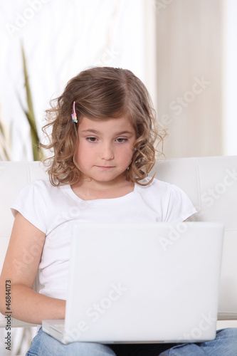 Photo: Little girl glued to laptop screen Little girl glued to laptop screen