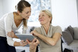 Girl showing tablet to elderly woman in wheelchair