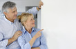 Senior couple pointing at message board