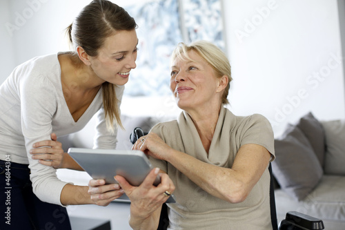 Photo: Girl showing tablet to elderly woman in wheelchair Girl showing tablet to elderly woman in wheelchair