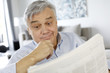 Senior man reading newspaper with puzzled look