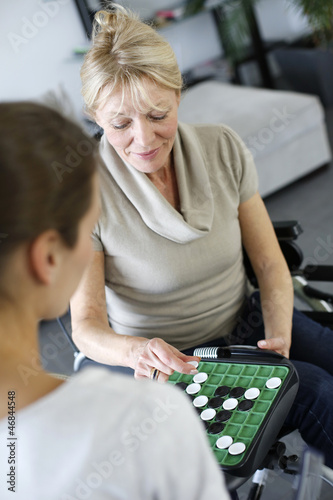 Photo: Young homecarer playing game with elderly woman Young homecarer playing game with elderly woman