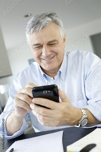Photo: Portrait of senior businessman using smartphone Portrait of senior businessman using smartphone