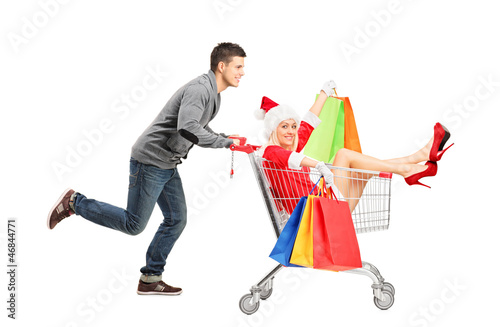 Photo: Happy guy pushing a female wearing christmas costume in a cart Happy guy pushing a female wearing christmas costume in a cart