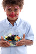Little boy made-up as a clown with bowl of candy