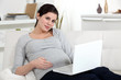 Pregnant woman resting laptop on lap