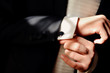 Close-up of a man in a tux fixing his cufflink.