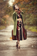 Style redhead girl with suitcase at beautiful autumn alley.