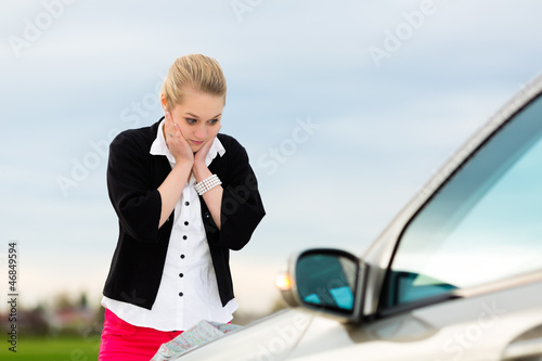 Photo: Junge Frau mit Karte auf Auto Motorhaube Junge Frau mit Karte auf Auto Motorhaube