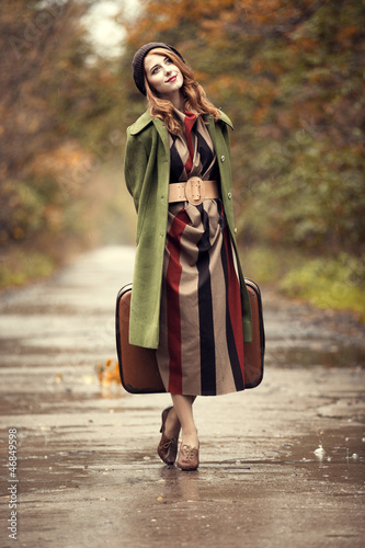 Photo: Style redhead girl with suitcase at beautiful autumn alley. Style redhead girl with suitcase at beautiful autumn alley.
