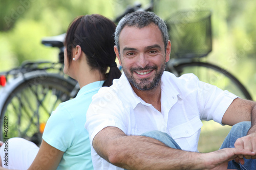 Photo: Couple sitting by their bikes in the countryside Couple sitting by their bikes in the countryside
