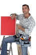 Carpenter posing with red poster