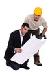 Construction worker consulting with an engineer over a drawing