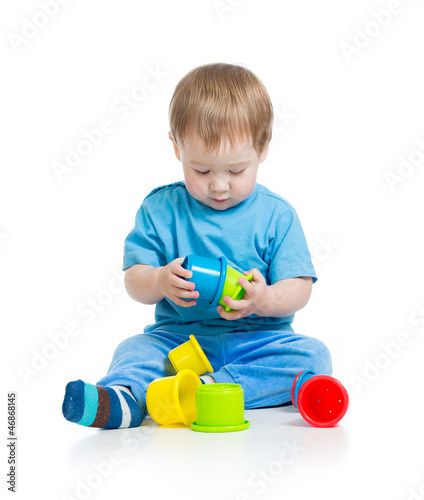 Photo: baby playing with colourful cup toys on floor, isolated over whi baby playing with colourful cup toys on floor, isolated over whi
