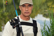 handsome middle-aged fisherman by riverside