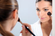 Woman applying blusher in a mirror