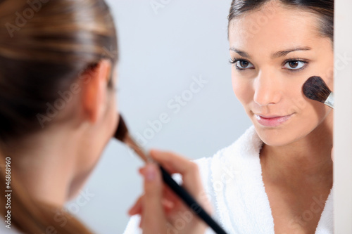 Photo: Woman applying blusher in a mirror Woman applying blusher in a mirror