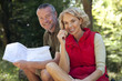 A mature couple sitting outdoors resting, man holding a map