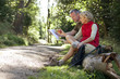 A mature couple resting beside a country path, looking at a map