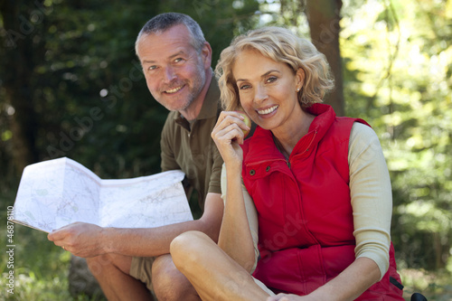 Photo: A mature couple sitting outdoors resting, man holding a map A mature couple sitting outdoors resting, man holding a map