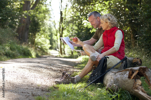 Photo: A mature couple resting beside a country path, looking at a map A mature couple resting beside a country path, looking at a map