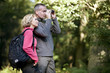 A mature couple in the countryside looking through binoculars