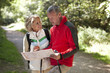 A mature couple walking in the countryside, holding a map