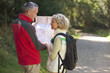 A mature couple walking in the countryside, holding a map