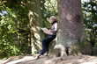 Photo: A mature woman resting on a tree, looking at a map A mature woman resting on a tree, looking at a map