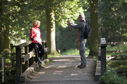 Photo: A man taking a photograph of his partner outdoors A man taking a photograph of his partner outdoors