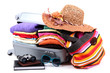 Closed silver suitcase with clothing isolated on white